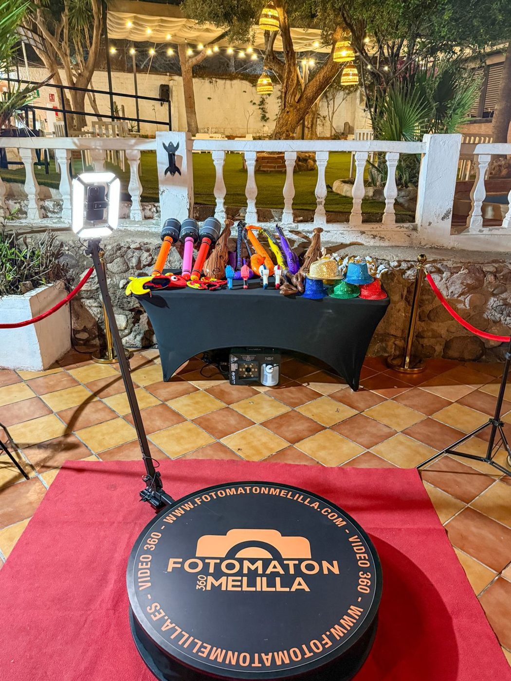 Plataforma de videomatón 360 con alfombra roja y mesa de atrezo en una terraza